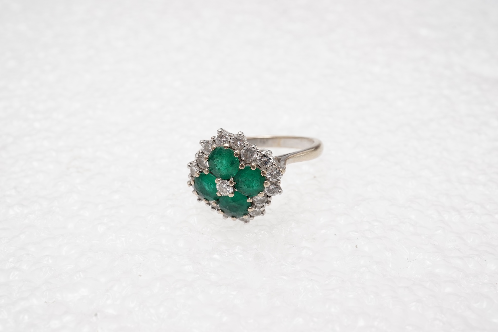 An emerald and diamond cluster ring